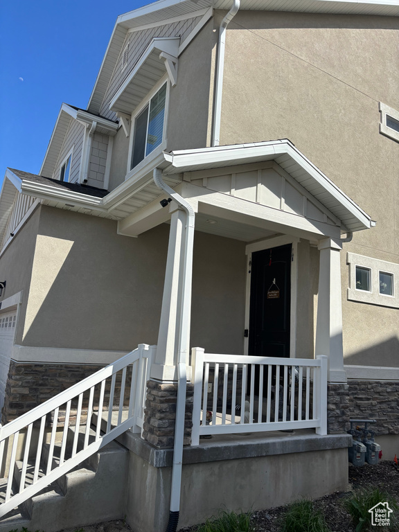 View of front of home featuring stone siding, a porch, and stucco siding