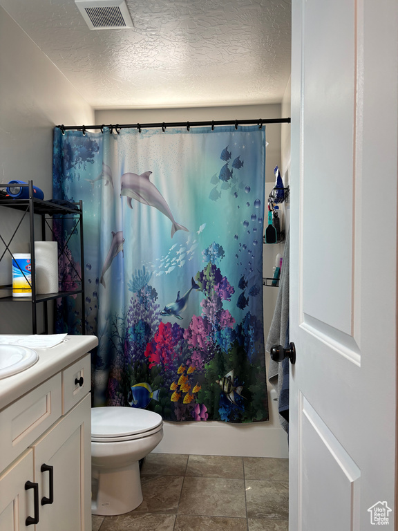 Bathroom featuring a shower with shower curtain, vanity, a textured ceiling, and toilet