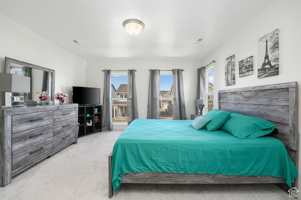 Bedroom featuring light carpet and multiple windows