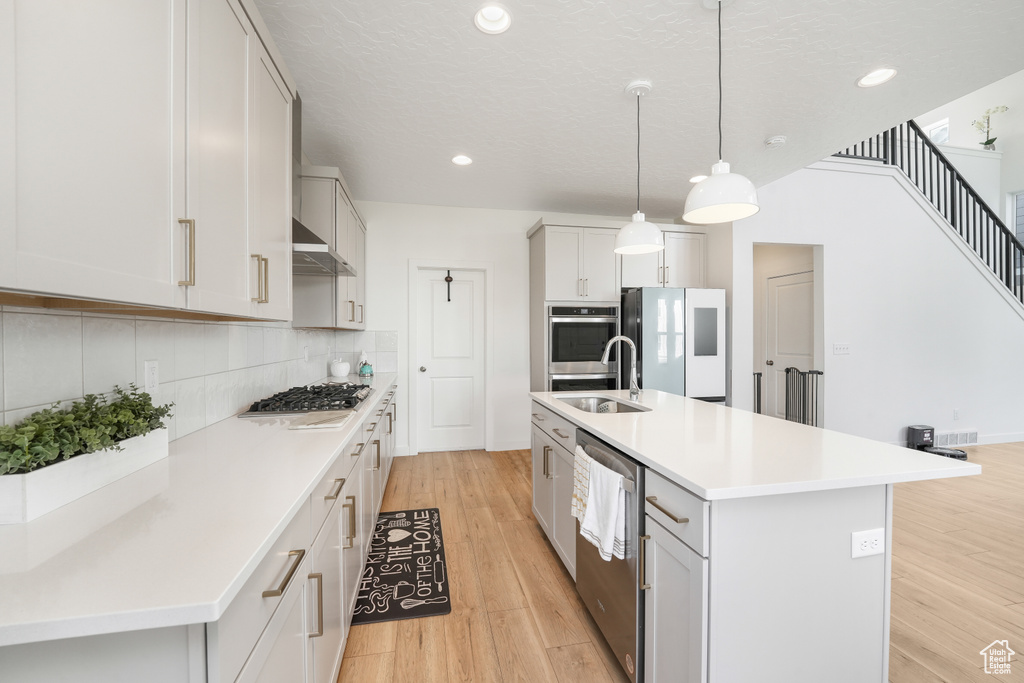 Kitchen featuring a sink, appliances with stainless steel finishes, recessed lighting, decorative backsplash, and light wood-style floors
