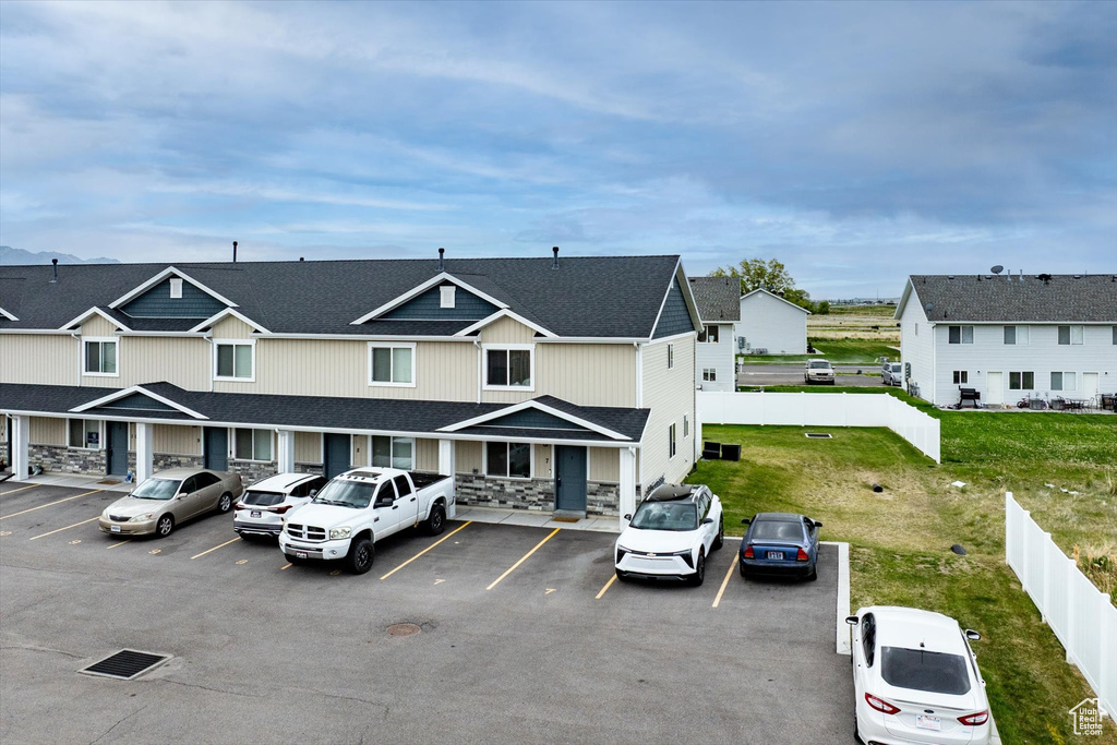 View of front of property with uncovered parking, stone siding, fence, and a residential view