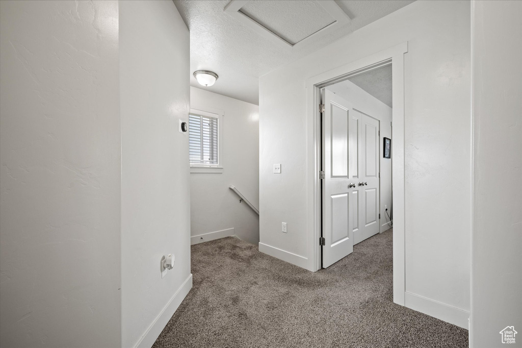 Corridor featuring attic access, an upstairs landing, carpet flooring, and baseboards