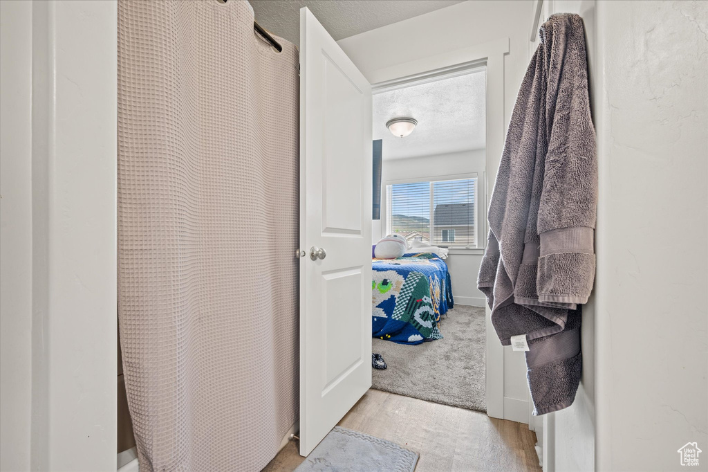 Ensuite bathroom with wood finished floors and curtained shower