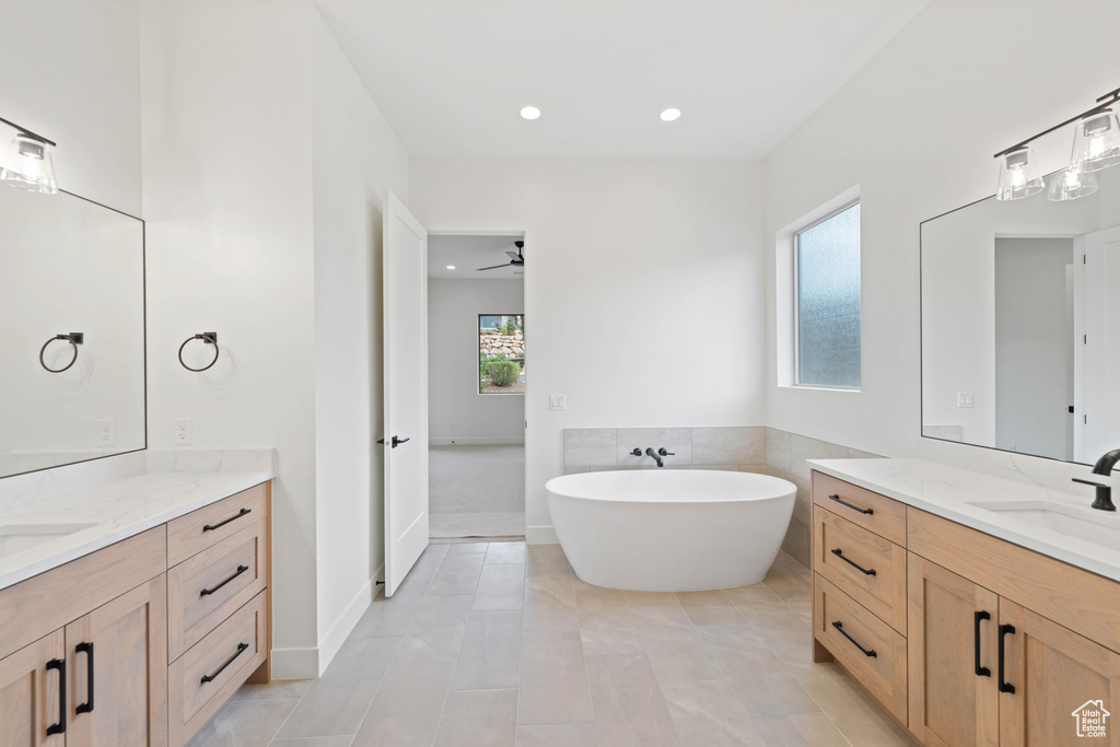 Bathroom with a freestanding tub, two vanities, recessed lighting, a ceiling fan, and tile patterned floors