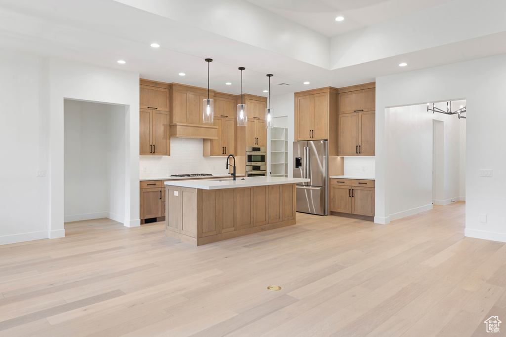 Kitchen with appliances with stainless steel finishes, recessed lighting, light countertops, decorative backsplash, and light wood-type flooring
