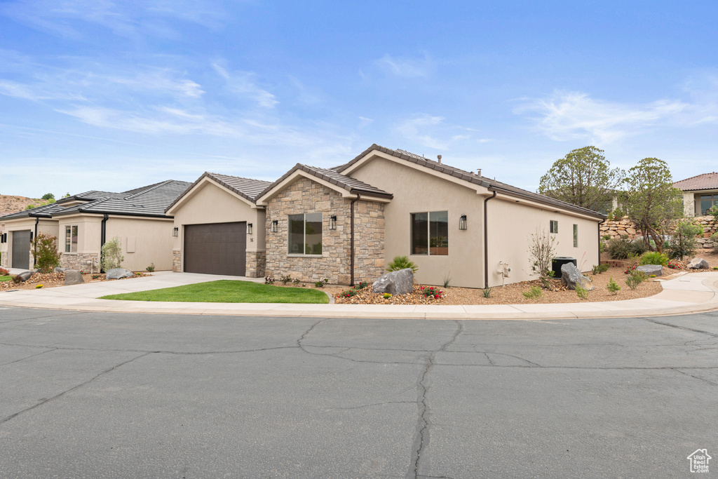 Ranch-style house featuring stucco siding, stone siding, driveway, and an attached garage
