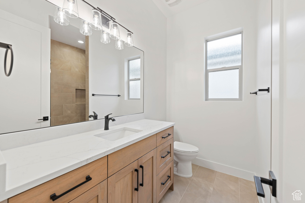 Full bath with healthy amount of natural light, vanity, toilet, and baseboards