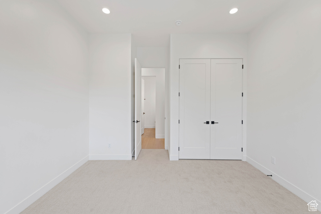 Unfurnished bedroom with light colored carpet, baseboards, a closet, and recessed lighting