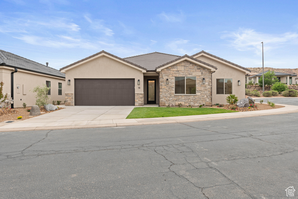 Ranch-style home with stone siding, concrete driveway, a garage, and stucco siding
