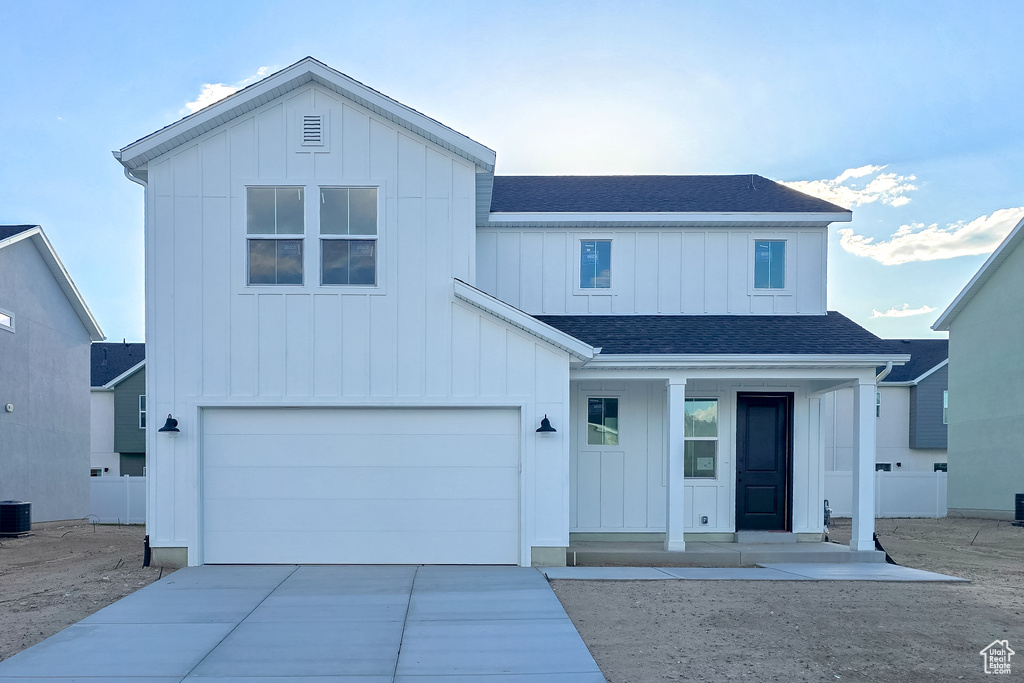 Modern farmhouse style home featuring board and batten siding, a shingled roof, and concrete driveway