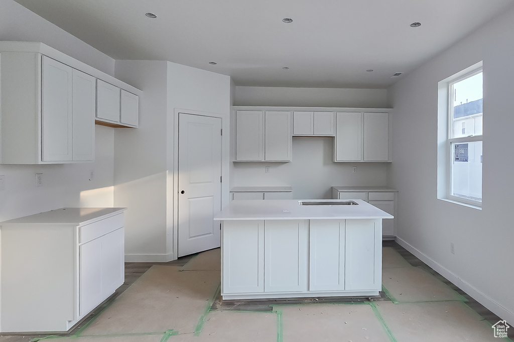 Kitchen with a center island, white cabinets, and baseboards