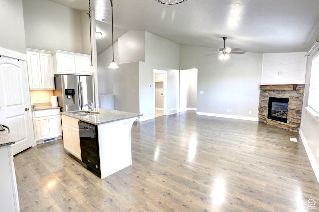 Kitchen with dishwasher, stainless steel refrigerator with ice dispenser, high vaulted ceiling, open floor plan, and ceiling fan