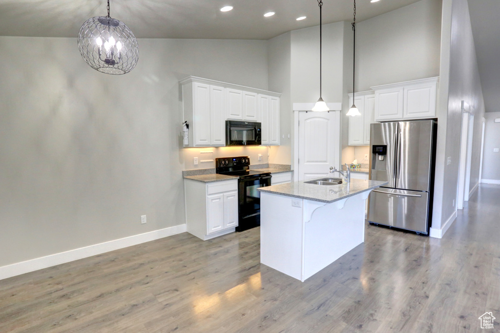 Kitchen featuring black appliances, high vaulted ceiling, baseboards, white cabinets, and a breakfast bar area