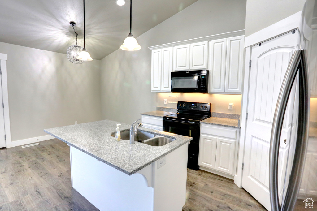 Kitchen with black appliances, vaulted ceiling, a sink, light wood-type flooring, and white cabinetry