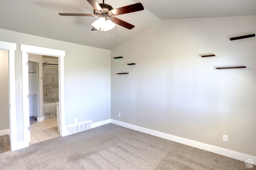 Unfurnished bedroom with carpet flooring, vaulted ceiling, baseboards, ensuite bath, and ceiling fan