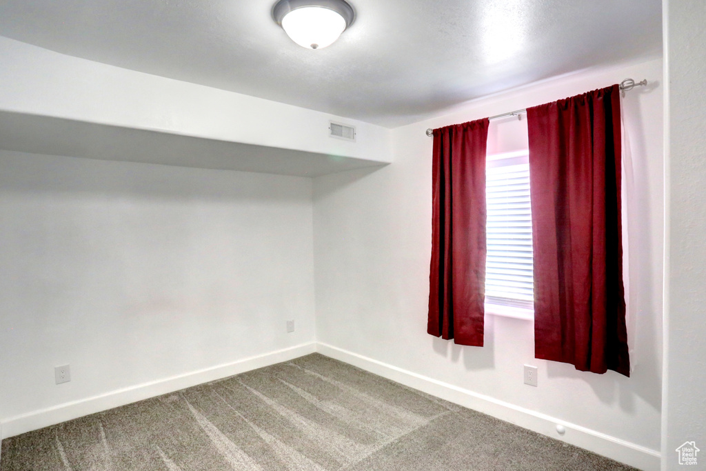 Empty room featuring dark carpet and baseboards