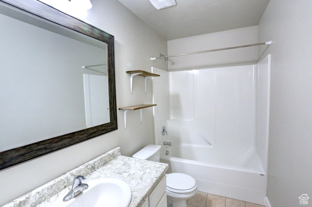 Bathroom with toilet, vanity, tile patterned floors, and shower / bathtub combination