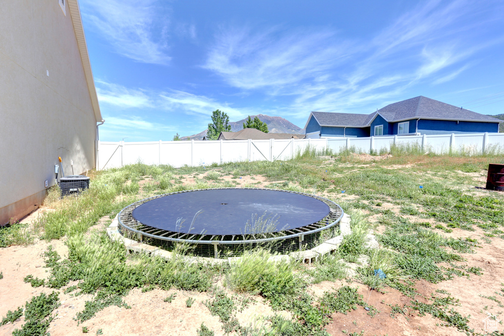 View of yard with a trampoline and fence