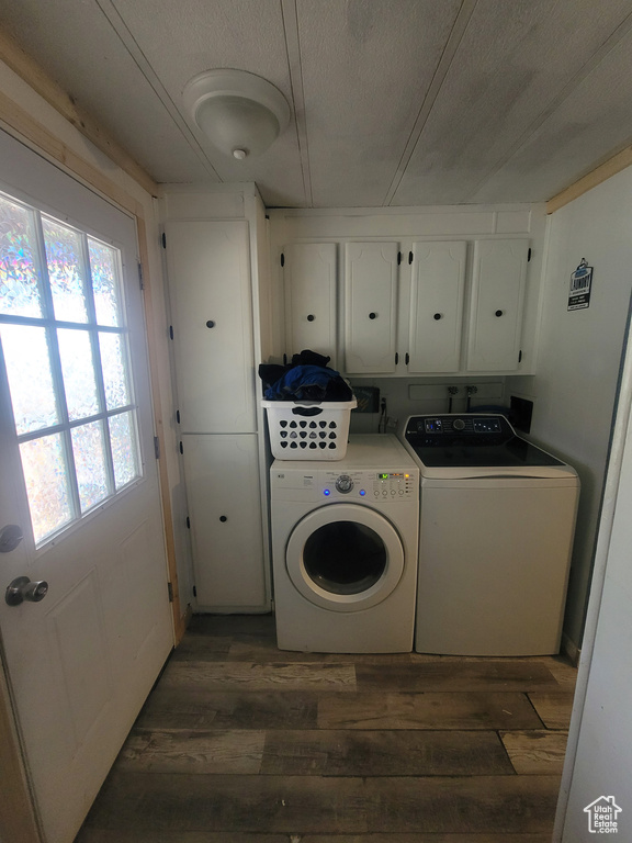 Laundry room with cabinet space, washer and dryer, wood-type flooring, and plenty of natural light