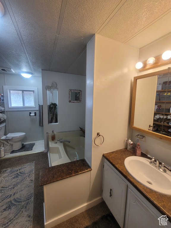 Full bathroom featuring vanity, a tub to relax in, toilet, and a textured ceiling