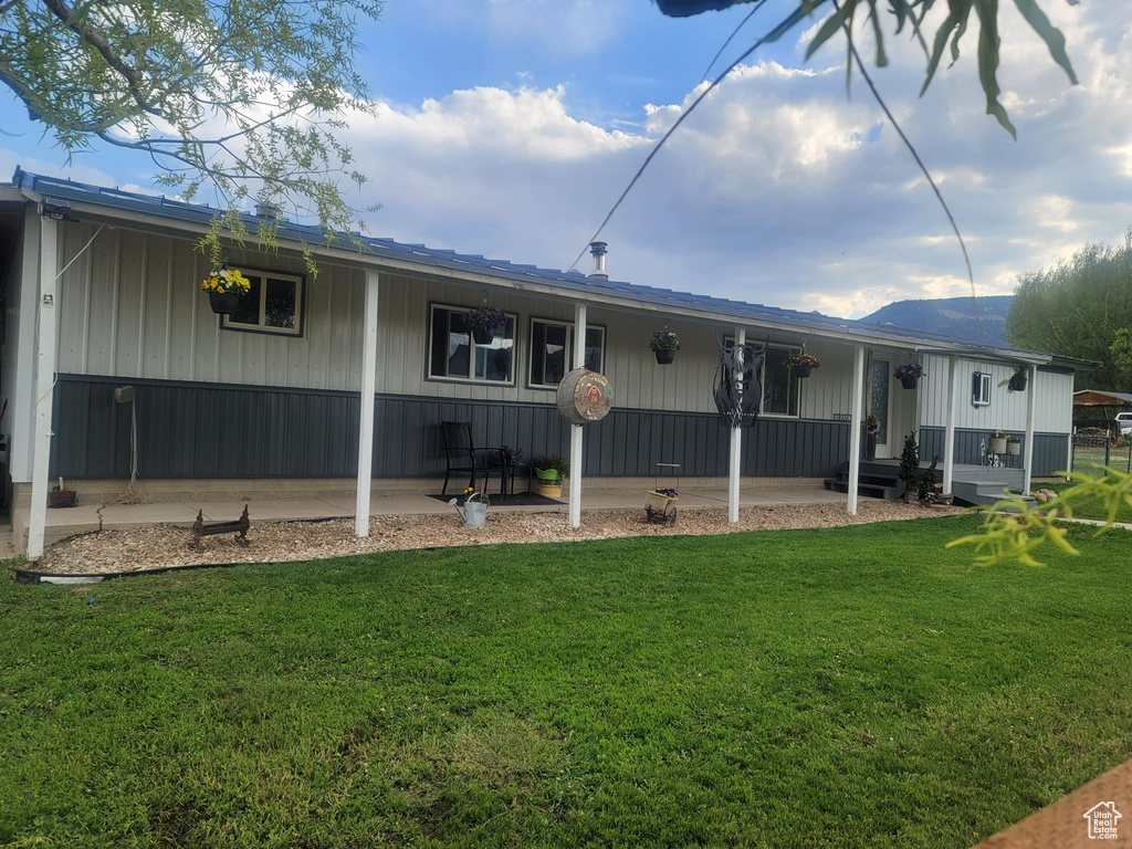 Rear view of property featuring a yard, a porch, and a mountain view