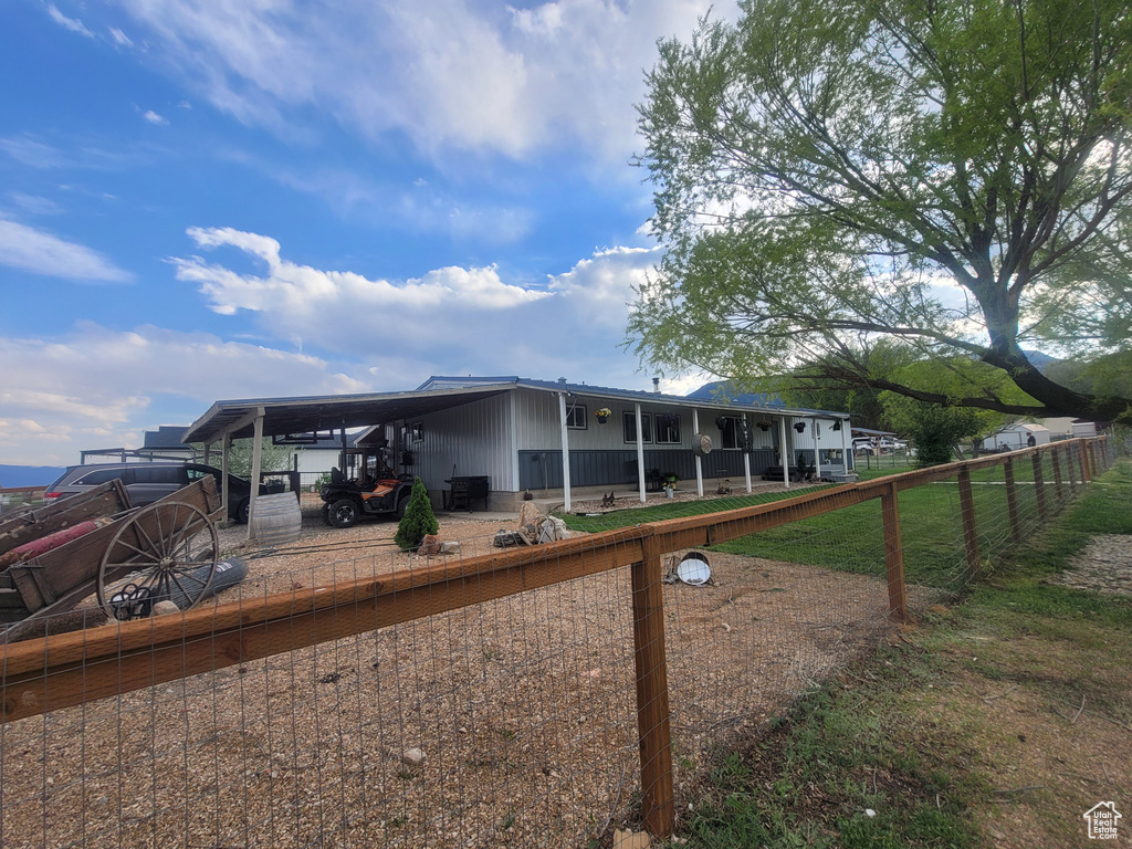Back of property featuring fence, covered porch, and a carport