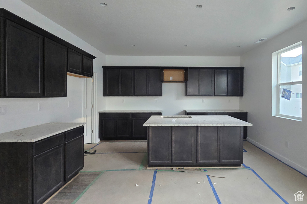Kitchen with baseboards, dark cabinetry, and a sink