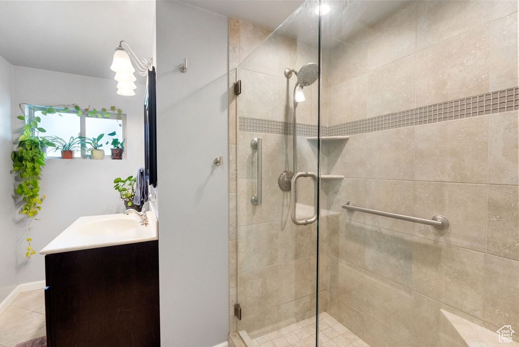 Bathroom with a shower stall, vanity, tile patterned flooring, and baseboards