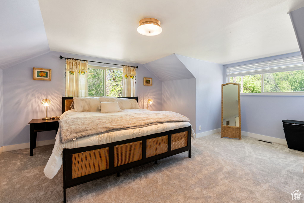 Bedroom featuring vaulted ceiling, multiple windows, carpet flooring, and baseboards