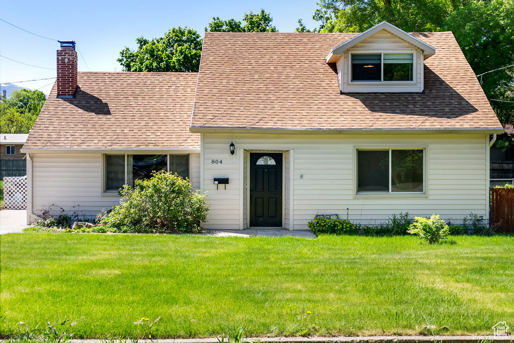 Cape cod-style house featuring a shingled roof and a chimney