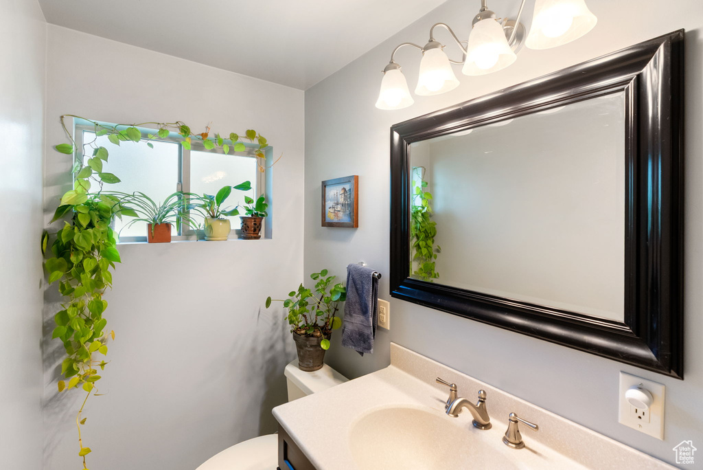 Half bathroom with toilet, vanity, and a chandelier