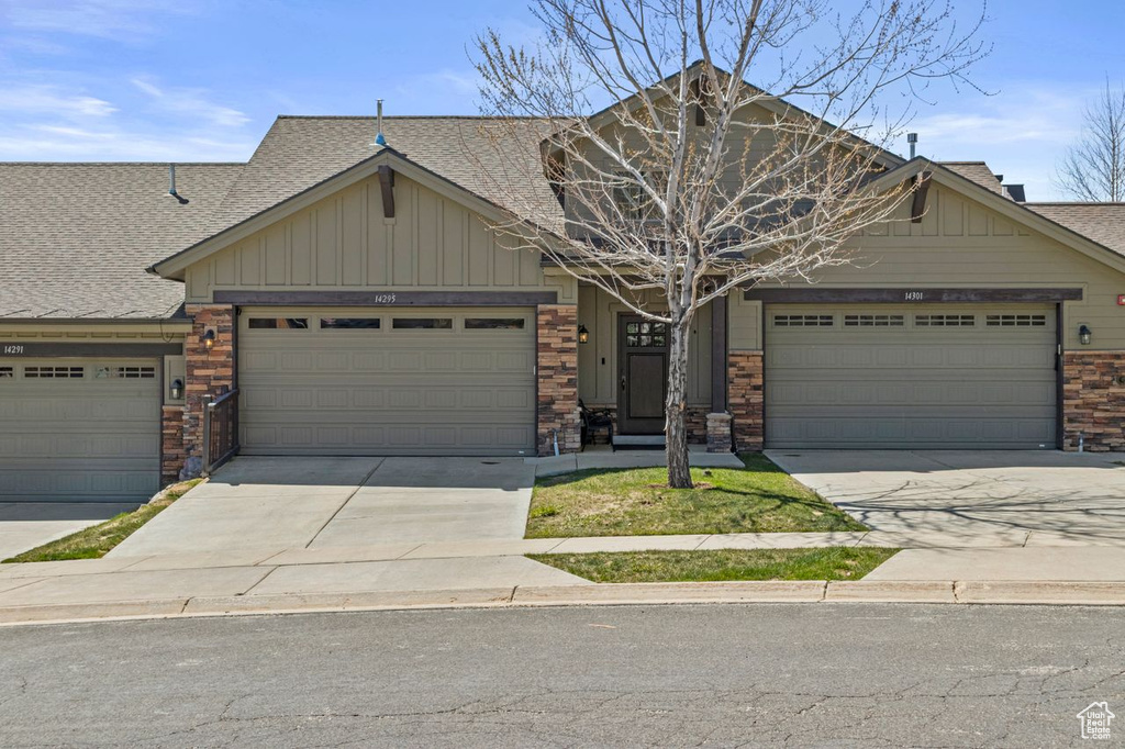 Craftsman inspired home featuring a shingled roof, board and batten siding, driveway, and a garage
