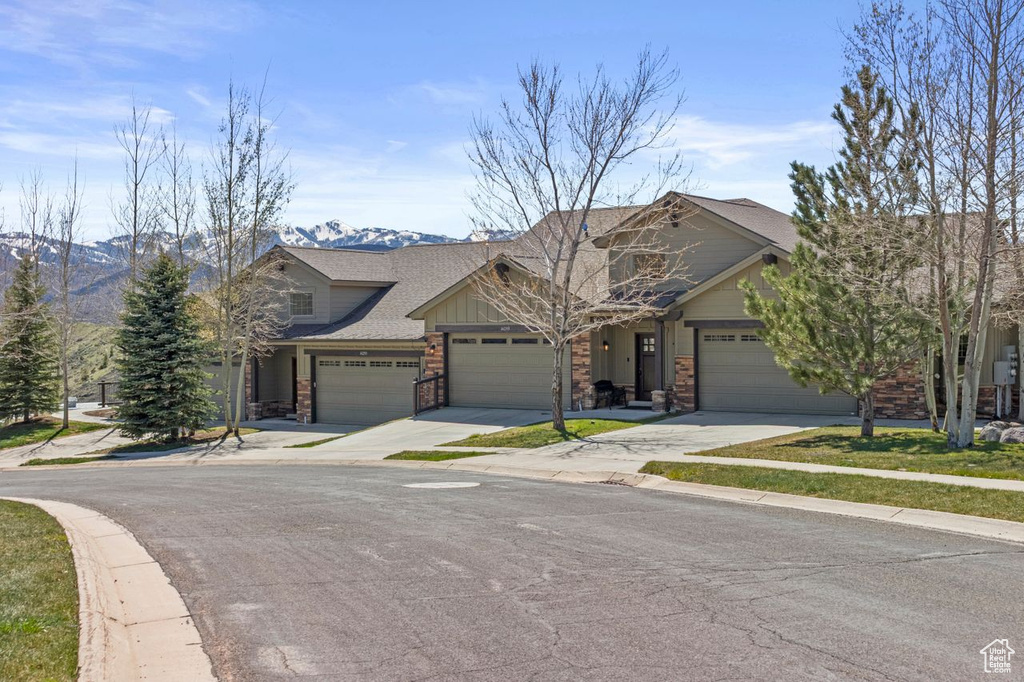 View of front of house with an attached garage, a shingled roof, a mountain view, and driveway