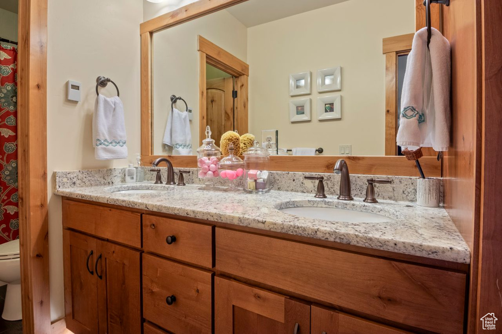 Bathroom featuring toilet, double vanity, and a sink
