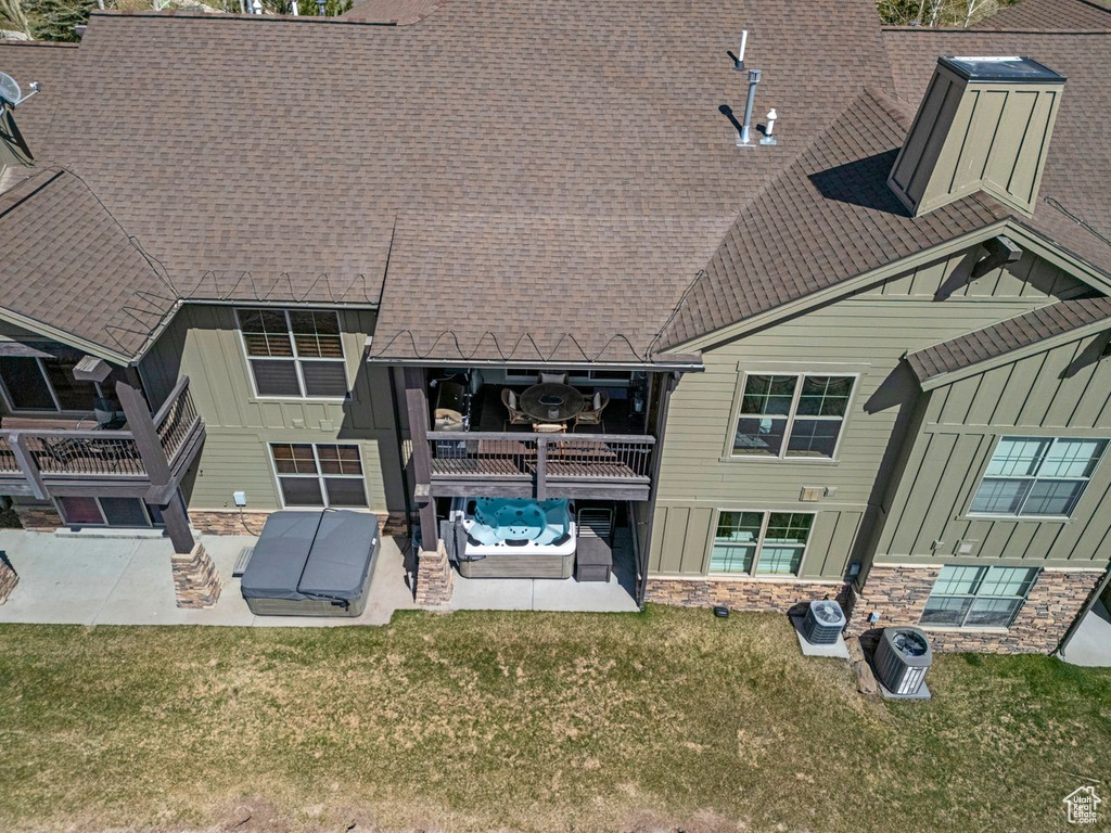 Rear view of house with a lawn, board and batten siding, a patio area, and stone siding