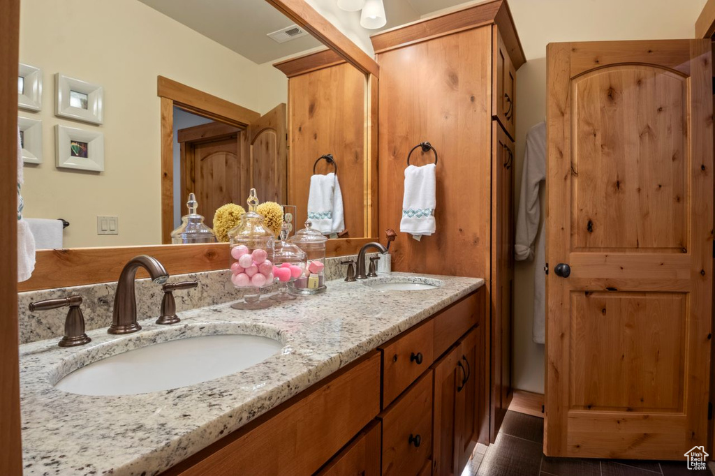 Bathroom with double vanity, visible vents, and a sink
