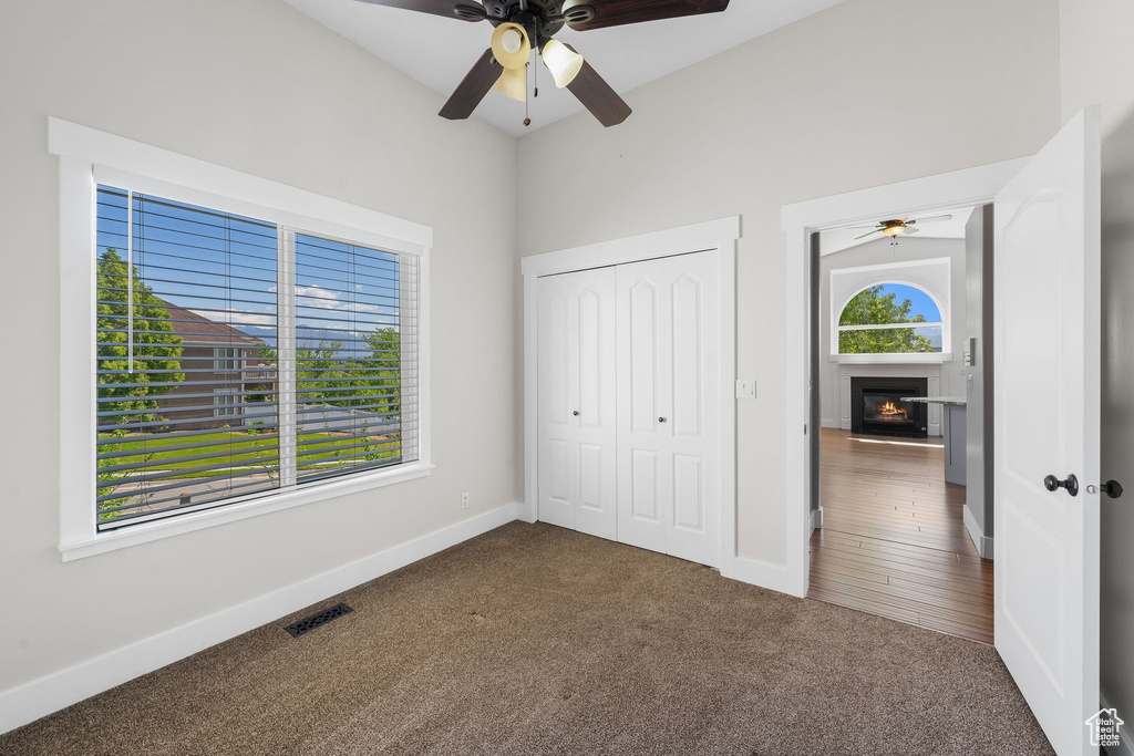 Unfurnished bedroom with carpet, multiple windows, a glass covered fireplace, and a closet