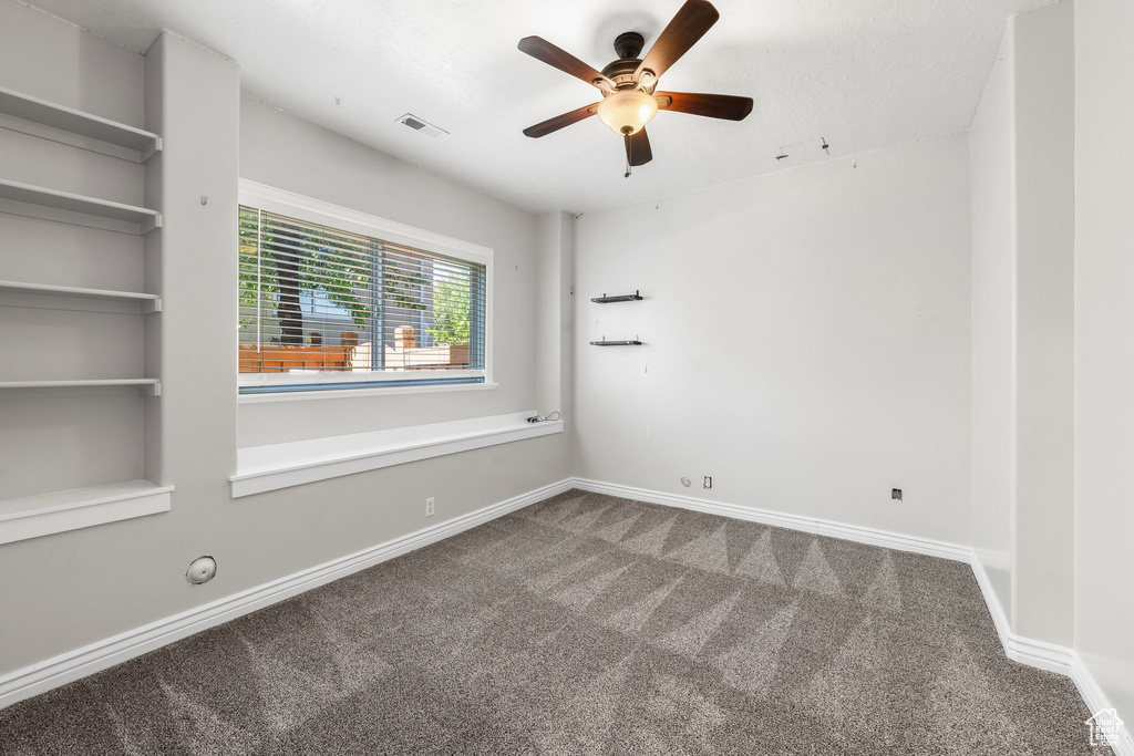 Empty room featuring carpet flooring, ceiling fan, and baseboards