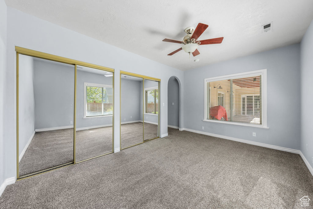Unfurnished bedroom with carpet, two closets, baseboards, and arched walkways