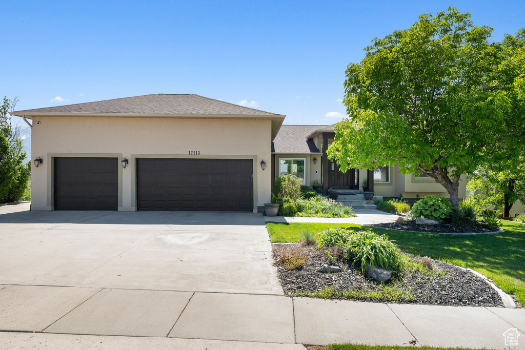 View of front of home with a garage, driveway, stucco siding, and a front yard