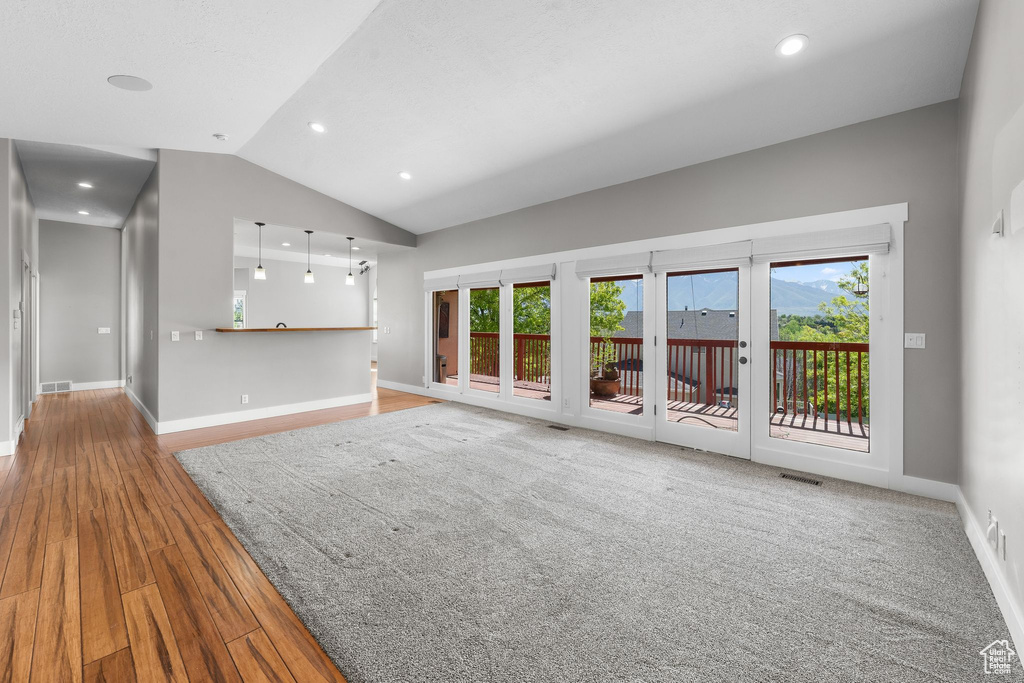 Unfurnished living room with wood finished floors, vaulted ceiling, baseboards, and recessed lighting