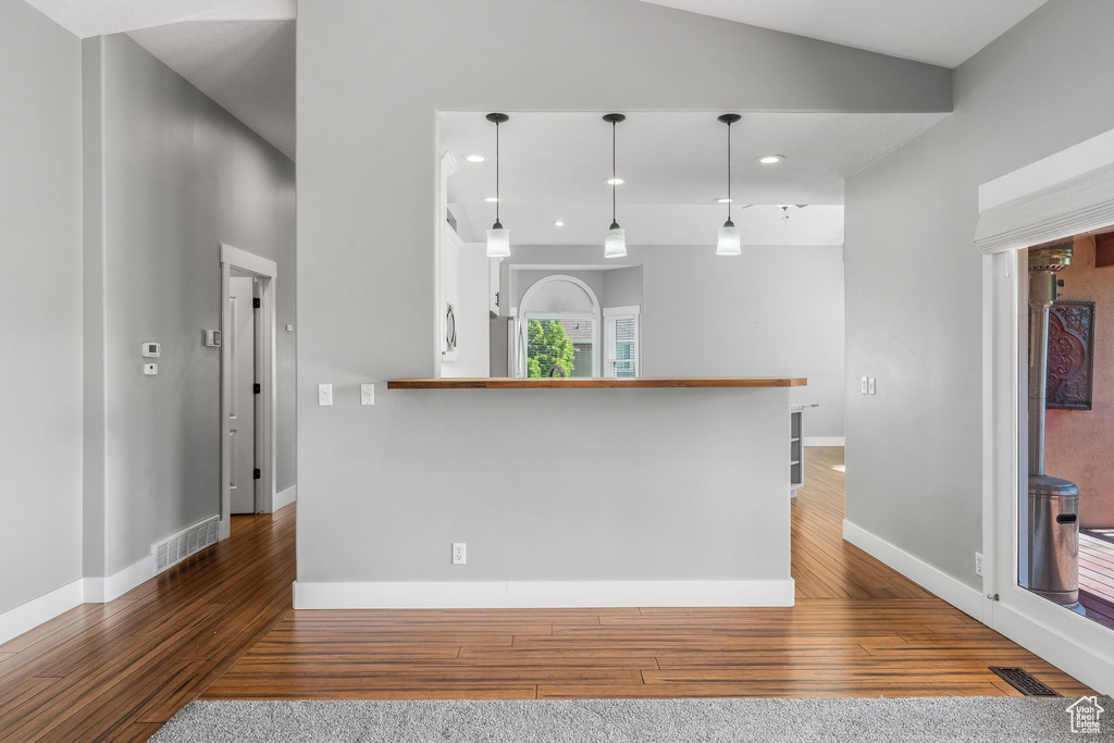 Kitchen featuring wood finished floors, baseboards, a peninsula, recessed lighting, and hanging light fixtures
