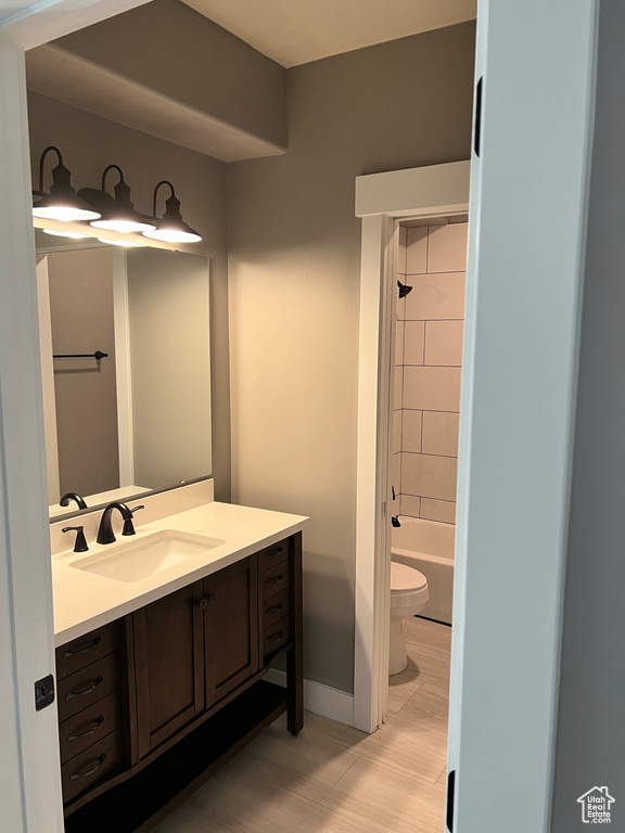Full bathroom featuring toilet, vanity, baseboards, and  shower combination