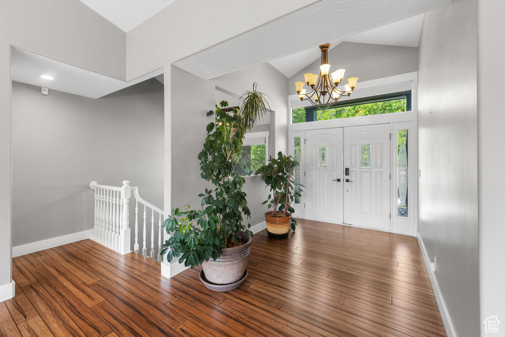Entryway with a chandelier, vaulted ceiling, hardwood / wood-style floors, and baseboards