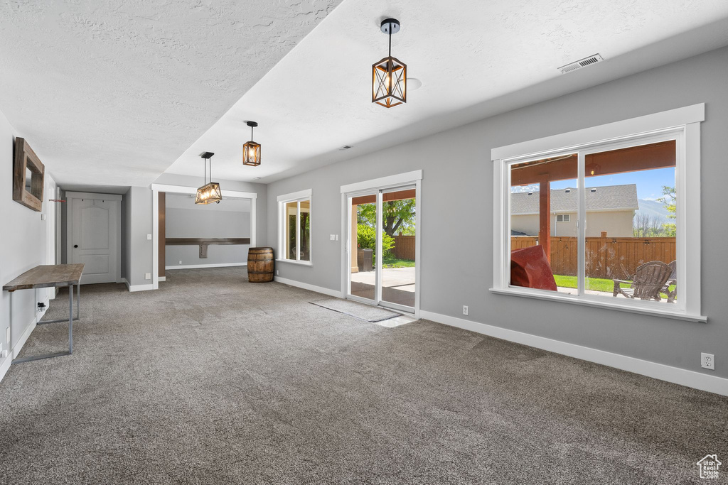 Unfurnished living room featuring baseboards, carpet flooring, and a textured ceiling