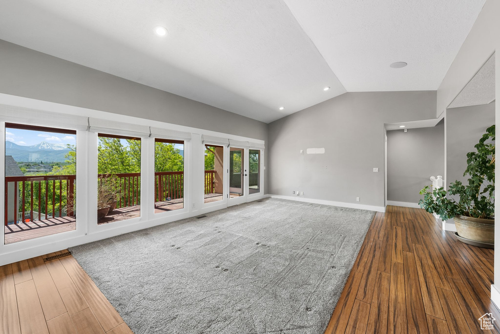 Unfurnished living room with vaulted ceiling, wood finished floors, baseboards, and recessed lighting