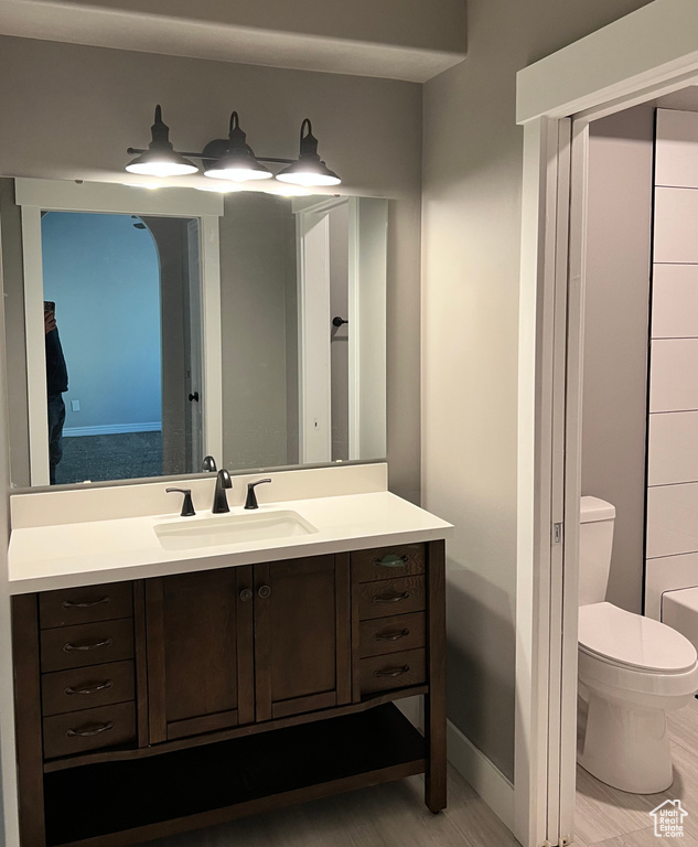 Full bath with toilet, vanity, and baseboards