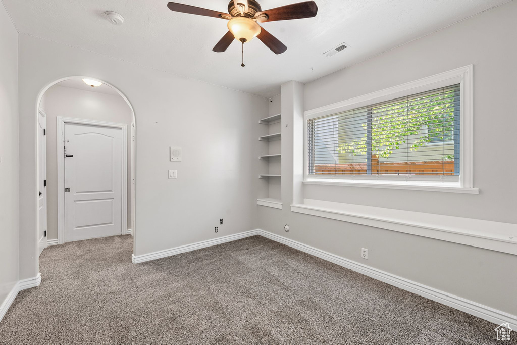 Unfurnished room with carpet flooring, ceiling fan, baseboards, and a smoke detector
