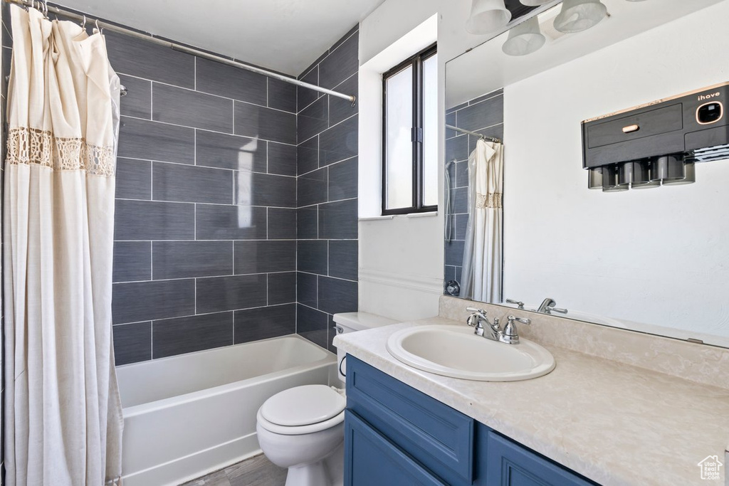 Bathroom featuring shower / bath combo with shower curtain, toilet, vanity, and wood finished floors