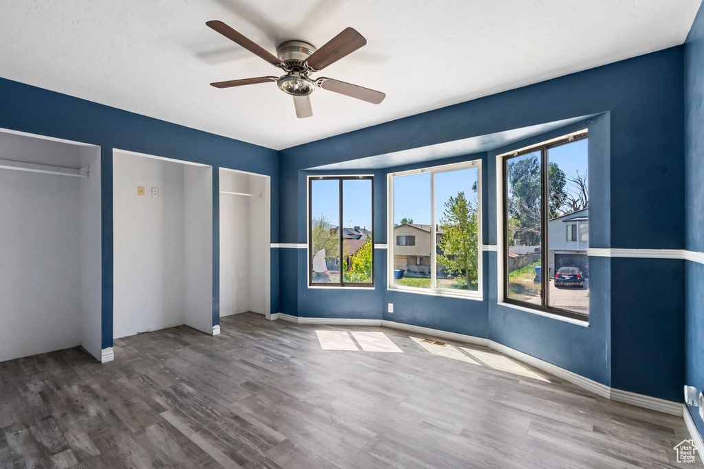 Unfurnished bedroom featuring multiple closets, wood finished floors, and baseboards